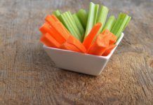 Bowl of carrot and celery sticks on wooden background By Denis Tabler