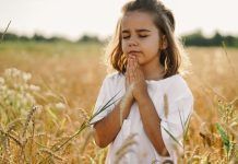young girl praying in a field