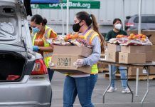 A volunteer loads food into the trunk of a vehicle