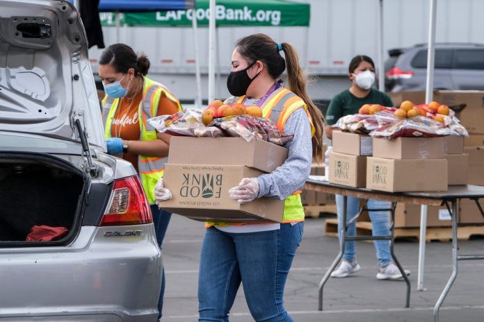 A volunteer loads food into the trunk of a vehicle