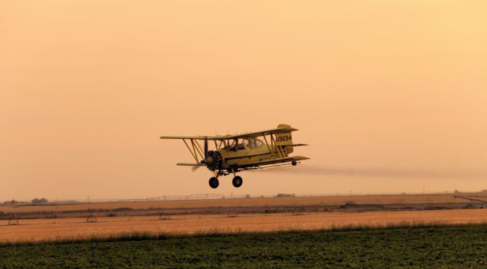 plane spraying pesticide on farm field