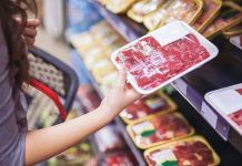 woman holding package of meat in grocery store